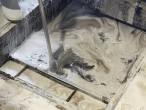 グリストラップ内の油汚れをブラシでかき混ぜて洗浄